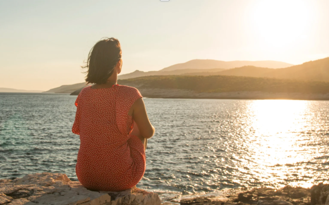 see yourself as Jesus sees you, woman sitting before a lake at sunrise